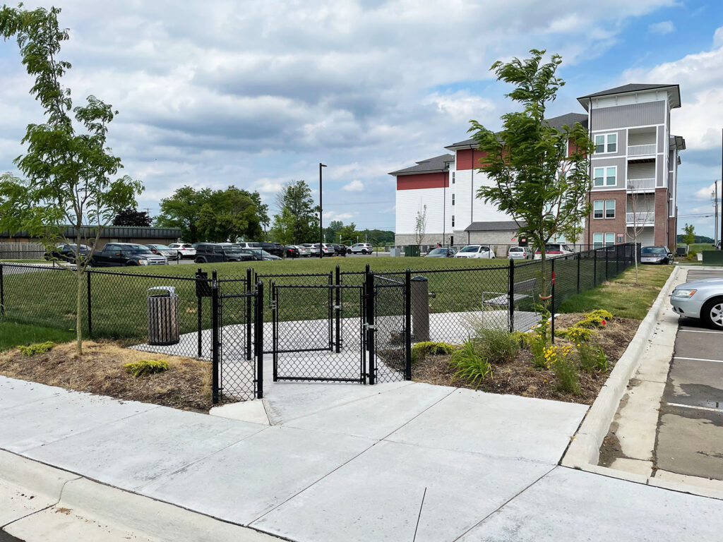 A fenced in dog park with a vestibule area to keep other dogs from escaping when another dog is entering or leaving.
